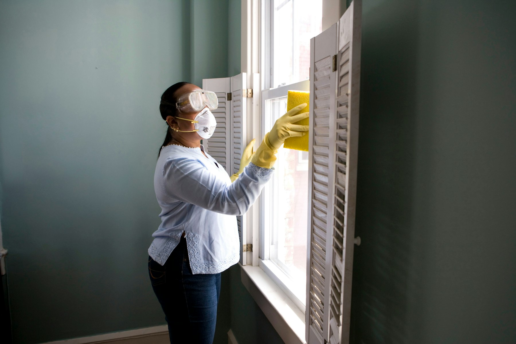 Maple Fresh cleaner wiping a bright window with yellow gloves
